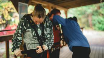 Wildplay trainer assisting people putting on their harnesses.