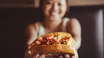 a very happy girl holding up a lobster roll at Rockfish Public House
