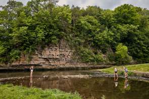 Two people fishing at a state park with a natural rock bluff behind them.