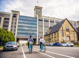 two people using bublr bikes, biking under the clocktower
