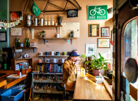 side view of a person sitting at a window drinking a cup of coffee at Sprocket Cafe