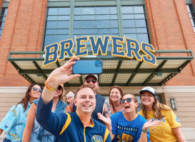 A group of Brewers fans smile in front of American Family Field