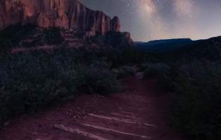 Starry Skies over a dirt hiking trail with logs laid out for steps and towering crimson cliffs in the background in Kolob Canyons, Ut.