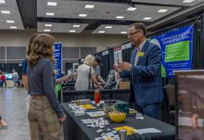 two women at Salina Business Expo 2025 talking to a business man at a booth