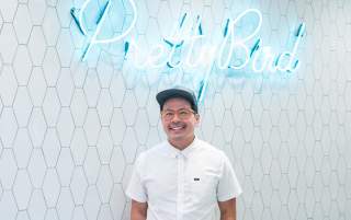 Viet Pham in front of the Pretty Bird sign