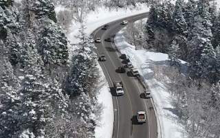 Cars driving on a slightly wet road in a snowy canyon