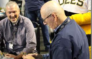 Salt Lake Bees Mascot standing behind two men sitting at a table talking