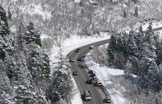 Cars driving on a slightly wet road in a snowy canyon