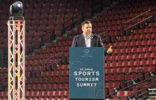Steve Starks standing at a podium that says Sports Tourism Summit
