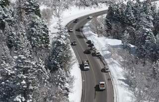 Cars driving on a slightly wet road in a snowy canyon