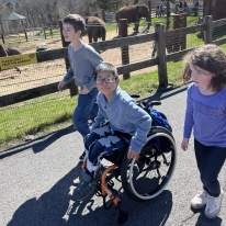 Three children at the Rosamond Gifford Zoo in front of the elephant exhibit. One child in a wheelchair