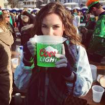 A woman drinking green beer out of a pitcher