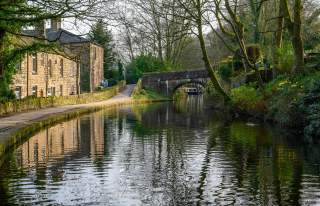 Canal with stone bridge and cottages in Oldham