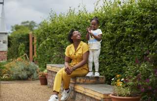 Adult and child sat on bench in front of plants at RHS Bridgewater