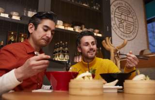 People eating noodles in restaurant with chopsticks