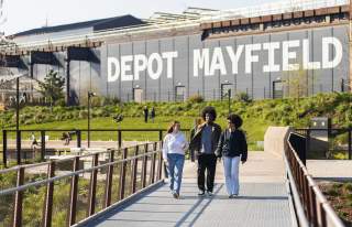 Friends walking along a bridge at Mayfield Park with Depot Mayfield sign in the background