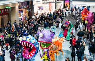 Procession of people in Halloween outfits through crowd in a shopping centre