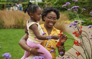 A woman holding a child looking at plants