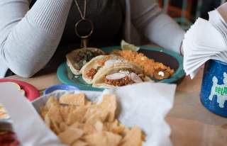 Person Sitting in Front of Tacos on Plate