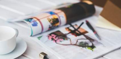 An open magazine with glasses, lipstick and a coffee cup