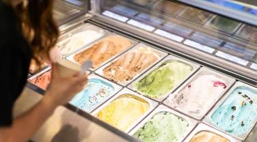 silver lining creamery worker scooping up a cup from the ice cream flavor options in Rapid City, sd