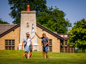friends high-five over golf hole