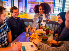 people sitting around a table, eating cheese curds