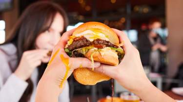 A messy burger held up with two hands