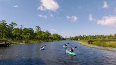 Three kayakers in river at Pascagoula River Audubon Center