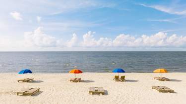 Biloxi Beach shoreline with multi-color umbrellas and chairs on a beautiful sunny day