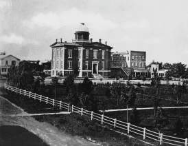Black and White Photo of the Courthouse in 1858 with the park in the square in the front.