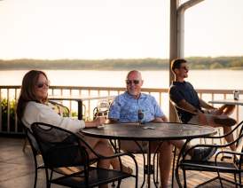 Three people enjoying drinks on the patio at the Point Restaurant which overlooks Lake Texoma