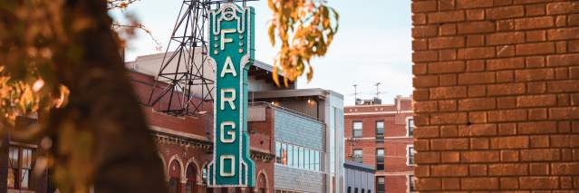 view of fargo theatre with a brick wall on the right side and fall foliage coming into the frame