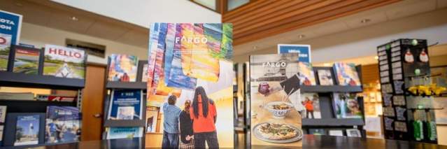 The Visitor Guide and Dining Guide standing upright on a tabletop in teh FM Visitors Center.