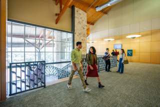 Image of a group of people dressed in business casual walking into the Palmer Events Center and chatting with one another.