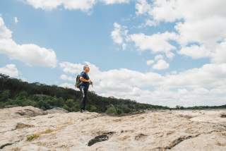 Image of a man standing on rocks looking out at the landscape in Barton Creek Greenbelt.