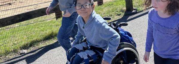 Three children at the Rosamond Gifford Zoo in front of the elephant exhibit. One child in a wheelchair