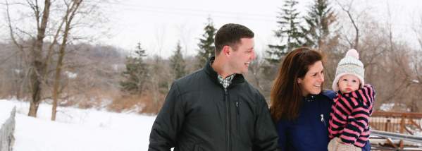 Couple with Baby Holding Hands and Walking through the Snow