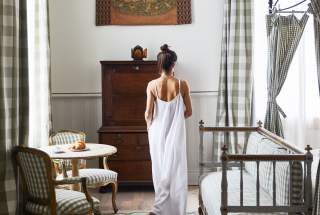 A woman in a white dress moves through a guest room at the upscale New Orleans boutique hotel Hotel Peter and Paul in the Marigny.