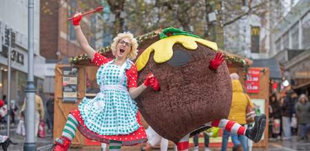 A person in a giant Christmas pudding costume