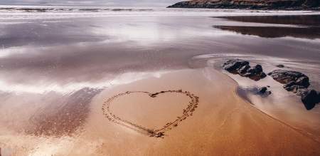 A heart drawn into wet sand on a beach