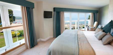 hotel bedroom with double bed and windows looking out over oxwich bay