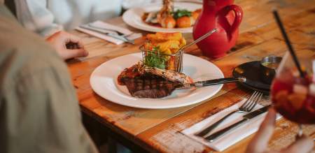 restaurant table with steak dish, drinks and cutlery