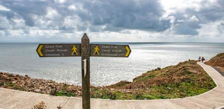 Coast path sign with the sea in the background.