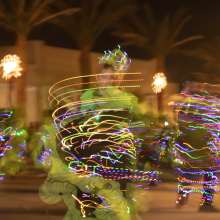 Gadsden folkloric dance group spinning with their green and black traditional dresses strung up with Christmas lights creating a light stream due to the long exposure of the photo.