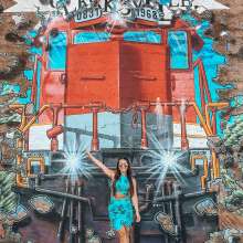 lady in front of a large train mural