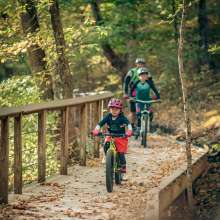 A family mountain biking through a trail in the fall at Clarksville's Rotary Park.
