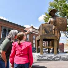 lady and daughter looking at a bronze statue