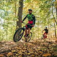 2 men riding bikes through woods