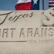 Close-up of a sand sculpture that has "Port Aransas the Island Life" carved into it.
